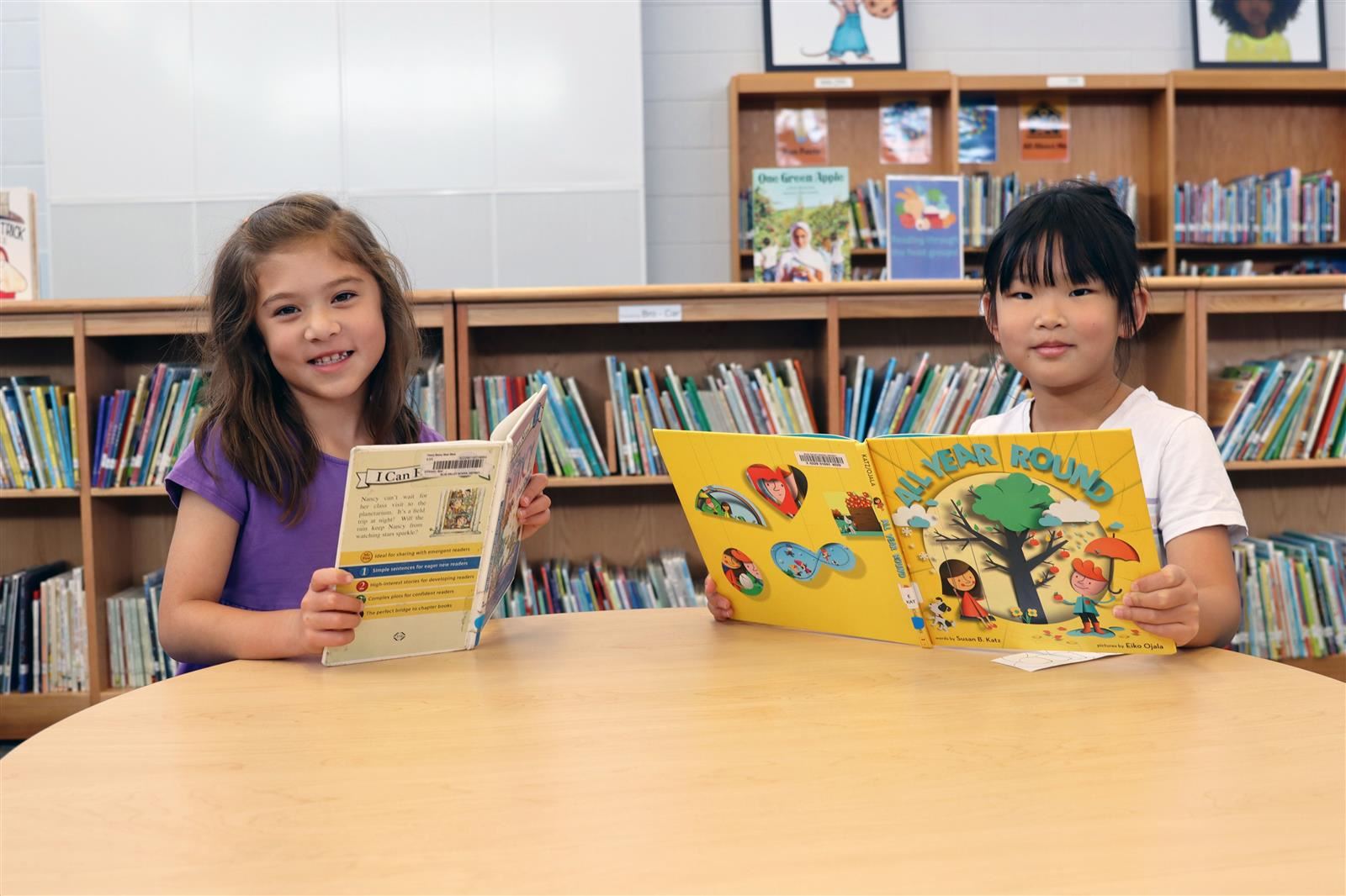 Two girls reading books and looking at the camera