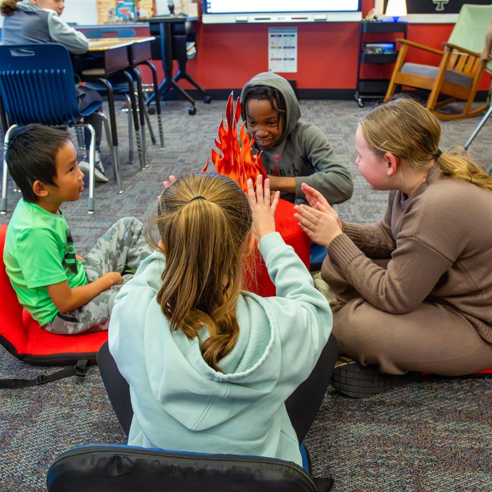 Students sit in a circle around a pretend campfire, representing our community core value.