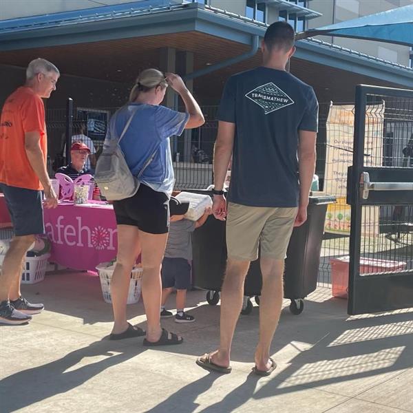 Image of a family dropping toilet paper into donation bin